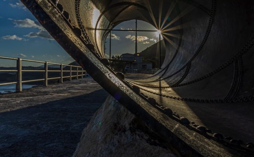 Inside a large metal pipe looking out at sunset