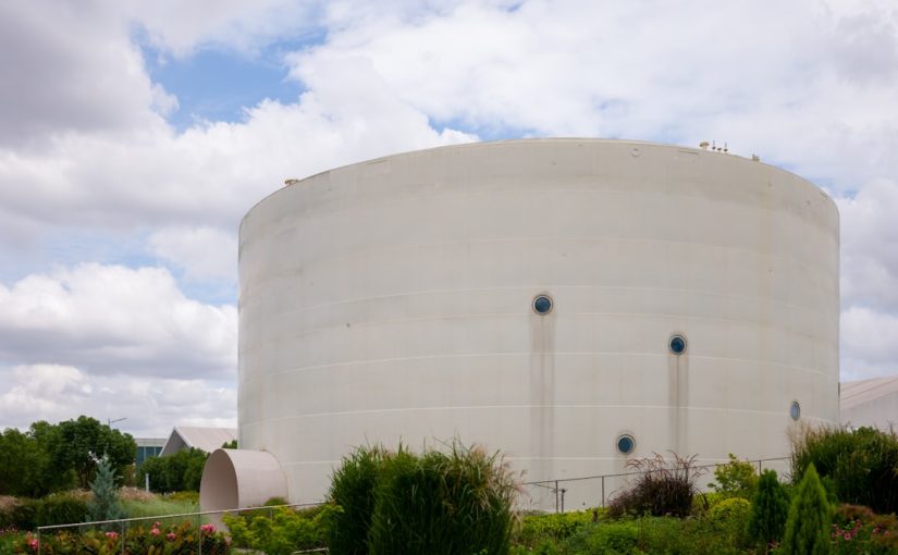 a large white water tank sitting next to a lush green field