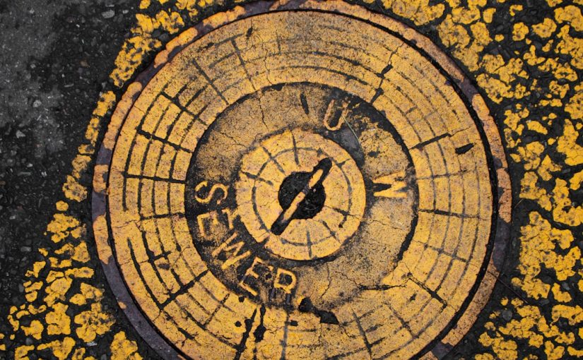 A round sewer cover marked with yellow paint.