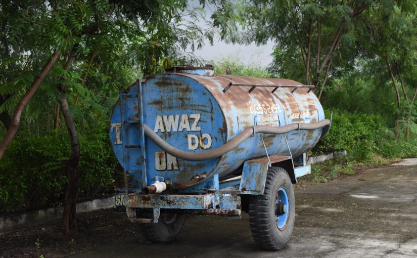 a large blue truck parked next to a lush green forest